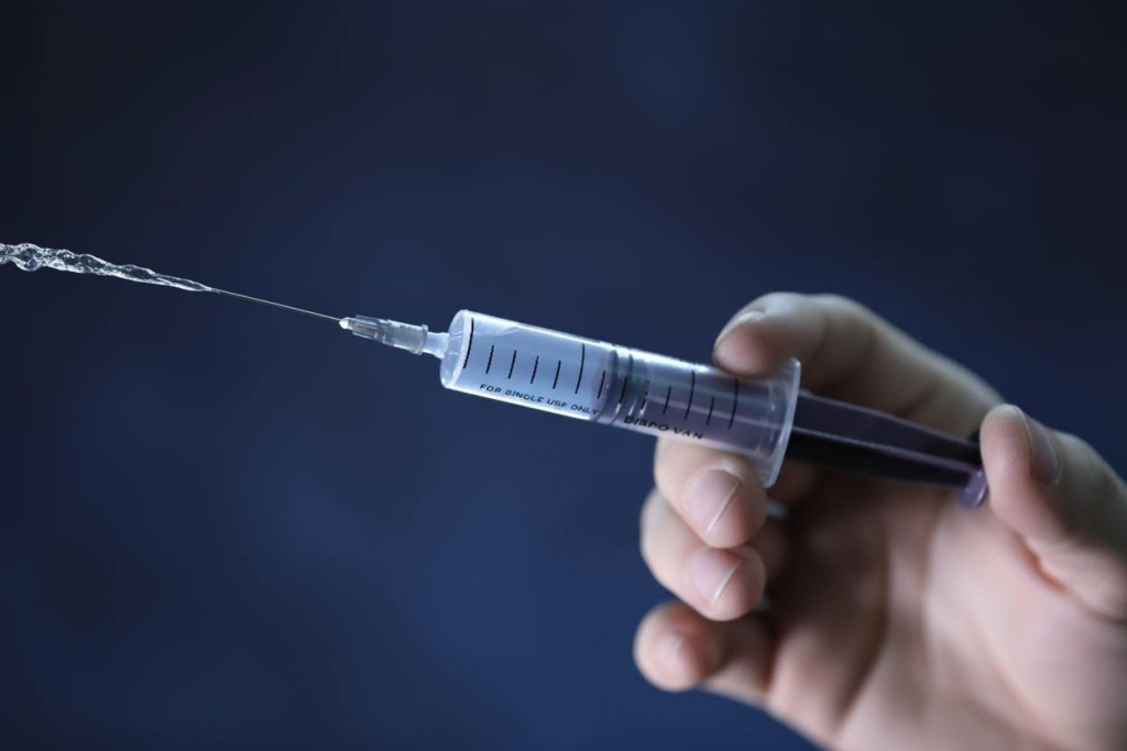 Close-up of a syringe squirting liquid symbolizing voltage as the pressure that pushes electric charge into motion